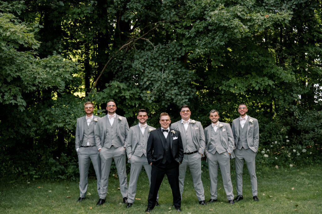 A groom and groomsmen in grey with a wedding photographer in Grand Rapids 