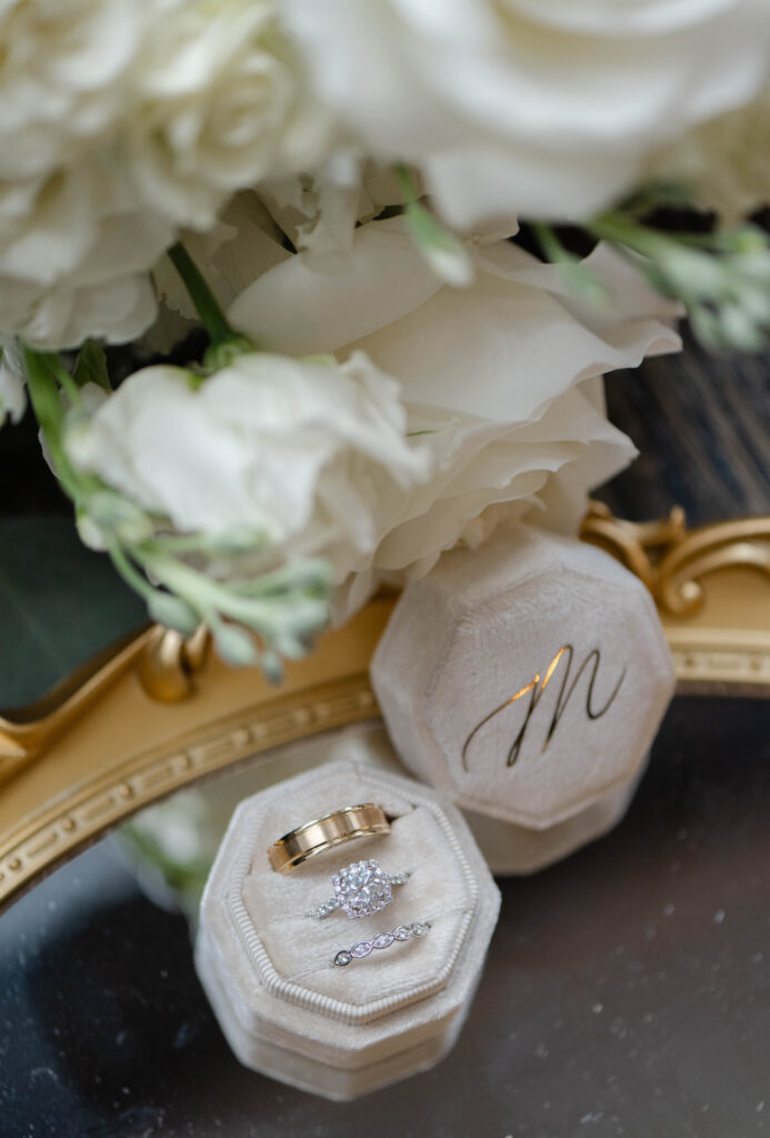 wedding rings in a velvet ring box with white roses