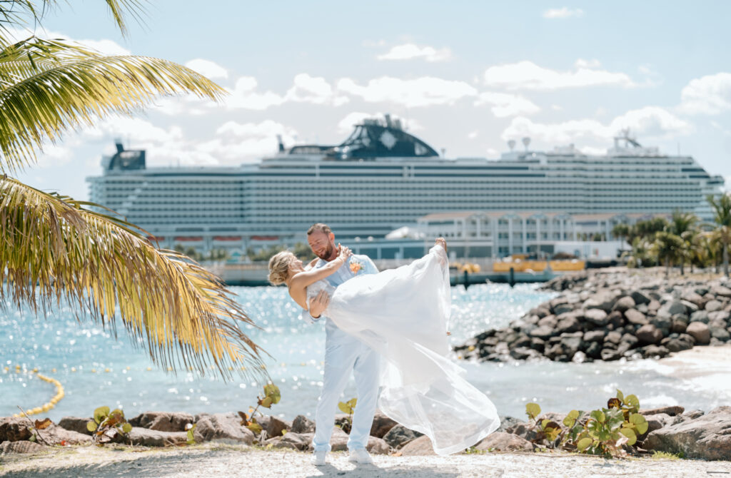 A groom picks up his bride in front of their cruise ship