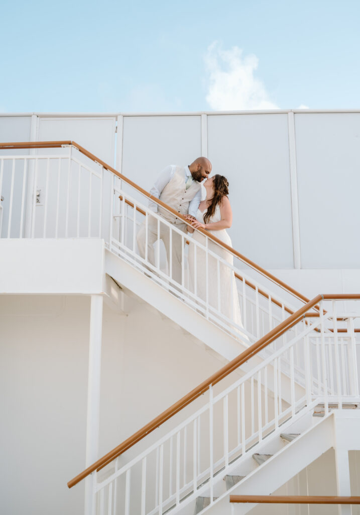 A bride and groom kiss on the stairs on a cruise ship