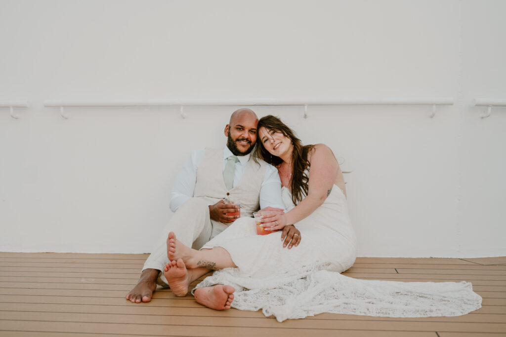 A bride and groom sit on deck on a cruise ship